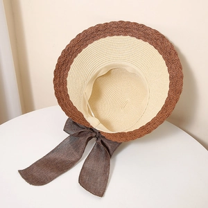 Close-up of contrast straw hat with scalloped edge and large dark brown bow detail