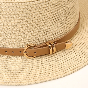 Close-up of a straw hat featuring a brown leather band and gold heart-shaped buckle