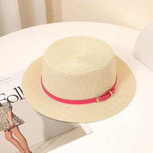 Détail d'un chapeau de paille à bord plat avec ceinture fuchsia et boucle dorée