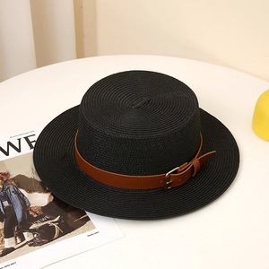 Detail of black straw boater hat with a brown leather strap and golden buckle buckle detail