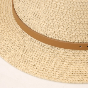 Close-up of fine woven straw texture and brown leather strap on summer sun hat
