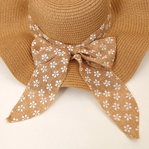 Close-up of woven straw sun hat with decorative floral print bow and textured ribbon detail