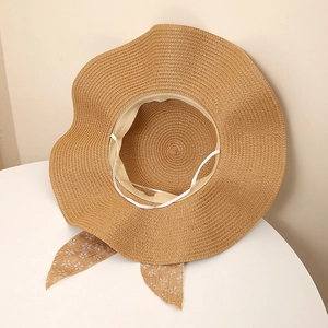 Detail of khaki straw sun hat with wavy brim and floral bow ribbon decoration