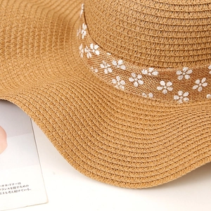 Close-up of woven straw sun hat texture with floral ribbon and minimalist bow detail