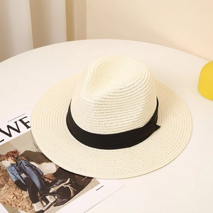 Detailed view of beige straw fedora hat featuring a fine weave and classic black ribbon trim