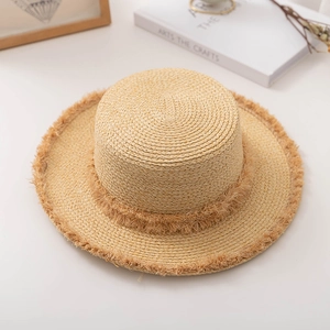 Détail de la texture d'un chapeau en paille tissée avec bords effilochés et haut plat