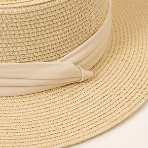 Close-up of a summer straw hat with natural weave texture and a decorative beige ribbon
