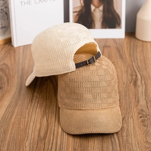 Checkered knit baseball caps in beige and camel with leather straps on a wooden table