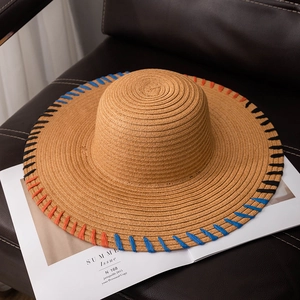 Handwoven wide brim straw hat with colorful rainbow edge stitching on a magazine