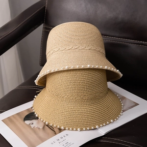 Detailed view of two khaki straw hats with elegant pearl trim and woven pattern