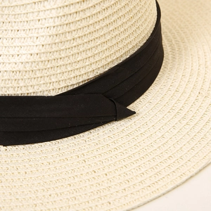 Close-up of beige straw sun hat featuring detailed weave pattern and black ribbon band