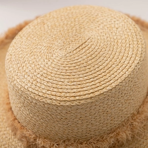 Gros plan sur le tissage en spirale paille fine et les franges bohèmes du chapeau de soleil