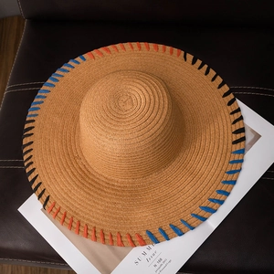 Wide brim straw sun hat with rainbow edge stitching on a magazine background