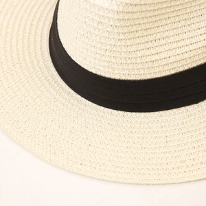 Close-up of fine straw weave and black ribbon detail on a light beige Panama hat