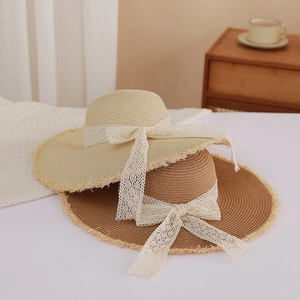 Summer straw beach hat with wide frayed brim and white lace bow in beige and brown