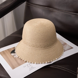 Detail view of woven straw cloche hat with elegant pearl trim on leather seat