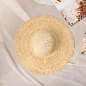 Détail du chapeau de paille à large bord avec bords effilochés et texture tressée