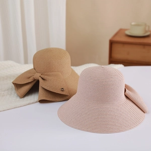 Women's woven straw sun hat with large bow and metal M-tag in camel and pink colors