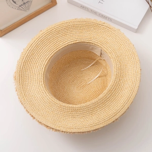 Vue détaillée du dessus d'un chapeau de paille à bord plat avec franges et lien interne