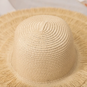 Gros plan d'un chapeau de paille à larges bords avec texture tissée et franges