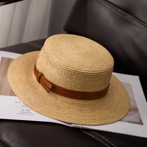 Detail of natural straw boater hat with dark brown leather band on a stylish leather chair