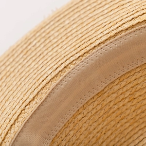 Gros plan sur la paille tressée naturelle et les détails du bandeau de ce chapeau