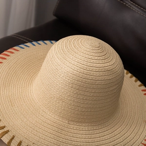 Close-up of the woven texture and colorful stitched rainbow edge of the straw sun hat