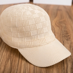 Detail shot of cream crochet checkerboard baseball cap on dark wood background