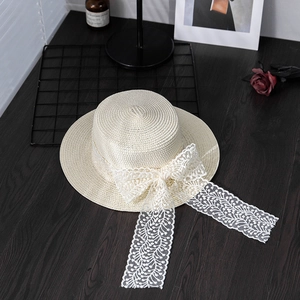 Detail view of summer straw hat with elegant white lace ribbon and bow decoration