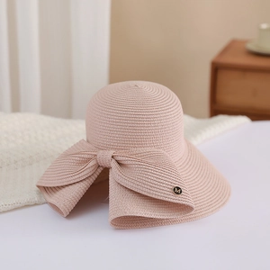 Detail of soft pink woven straw sun hat with large bow and metallic M logo accent