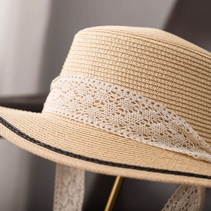 Gros plan sur la texture fine en paille et le ruban de dentelle blanche d'un chapeau d'été