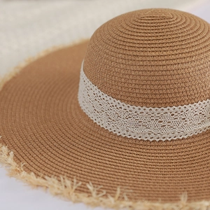 Close-up of the woven texture and white lace ribbon on this wide-brim straw beach hat