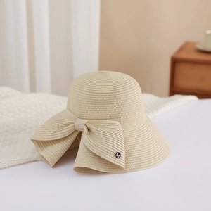 Detailed texture of khaki woven straw hat with elegant bow and metallic M letter logo