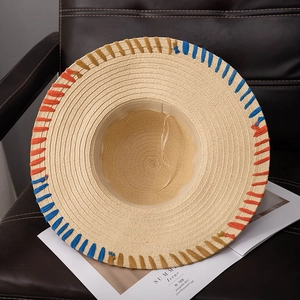 Detail of wide brim straw sun hat with decorative orange, blue, and yellow woven edges