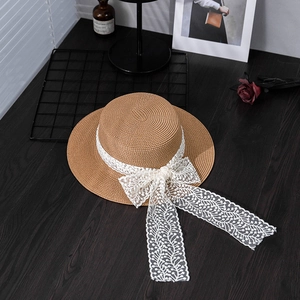 Detail of brown straw flat top hat with elegant white lace ribbon and large side bow