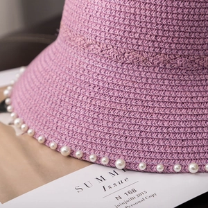 Detail of lavender straw hat brim featuring elegant pearl trim and woven texture