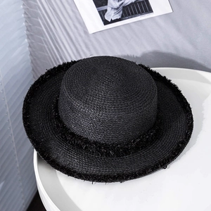 Detailed view of the frayed edge and woven texture on a black straw boater hat