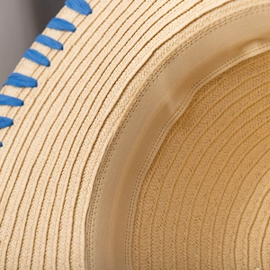 Detailed close-up of straw sun hat featuring blue criss-cross weave and textured fiber