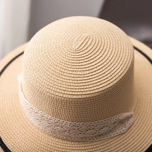 Gros plan du tressage en paille et du ruban en dentelle blanche sur le chapeau