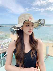 Detailed straw sun hat with pink flower embroidery and black mesh brim on beach