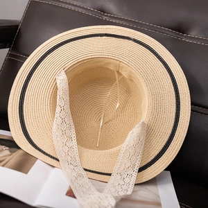 Détail d'un chapeau de paille à large bord avec bordure noire et ruban en dentelle blanche