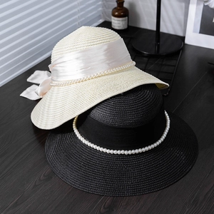 Close-up of woven straw hat texture with silk ribbon bow and pearl bead detailing