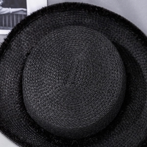 Close-up of black straw boater hat showing fine woven texture and frayed edge detail