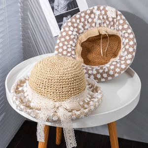 Detail of straw sun hat featuring white lace flowers and an elegant bow decoration