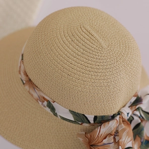 Detail of straw hat weave and tropical flower ribbon bow on beige sun hat brim