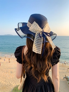 Vista posteriore di un cappello di paglia blu scuro con grande fiocco in pizzo bianco