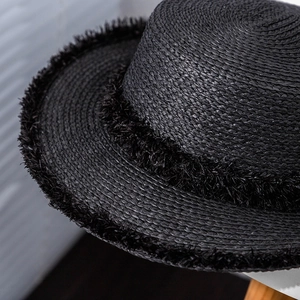 Macro shot of black straw boater hat with frayed fringe edges and fine woven texture