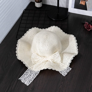 Detail of summer straw hat showing white lace bow and delicate wavy lace edge