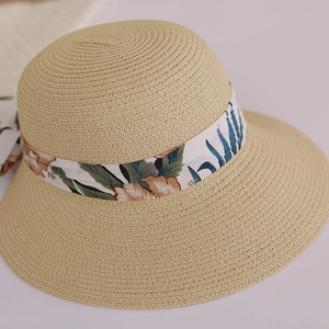 Detailed view of woven straw sun hat texture with tropical flower patterned ribbon
