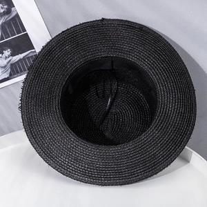 Detailed top view of a black woven straw hat featuring a flat top and wide brim style